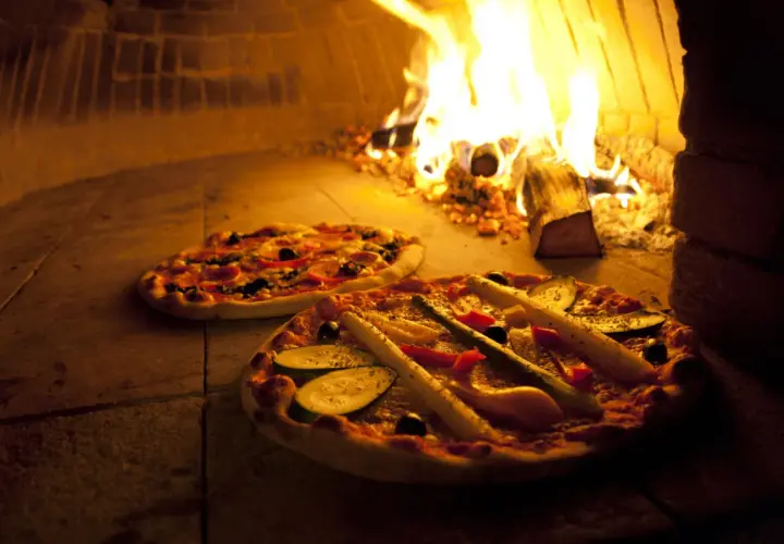 Zwei Pizzen im Holzofen, die Hitze des Feuers sorgt für die perfekte pizza ofen temperatur.