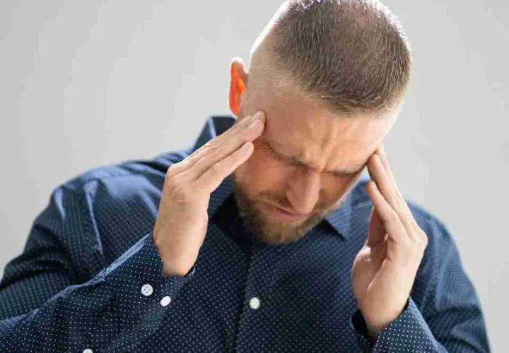 Uomo con le mani sulle tempie, sofferente, cerca sollievo per come eliminare le vertigini.