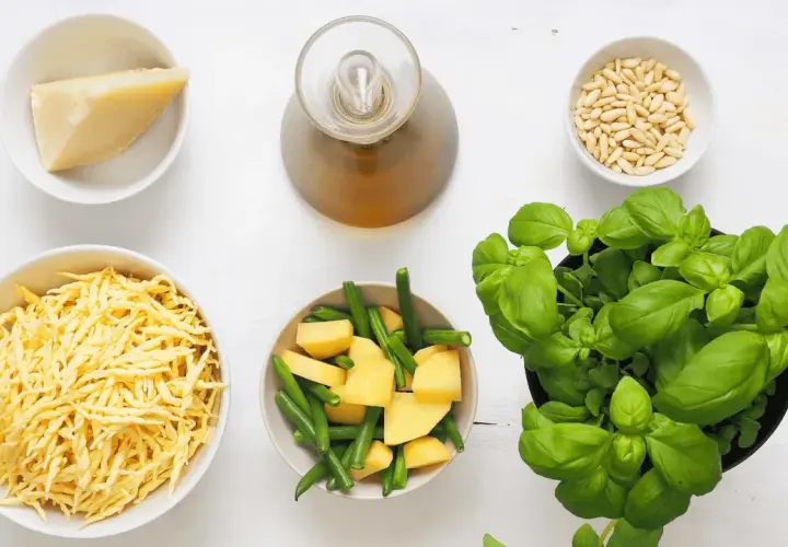 Ingredienti per un pesto senza pinoli: basilico fresco, formaggio grattugiato, patate, fagiolini, olio e aglio.