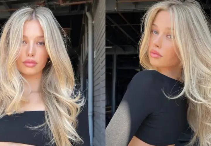 Blond włosy z subtelnym scandi hairline, falowane i pełne objętości, opadają na ramiona.