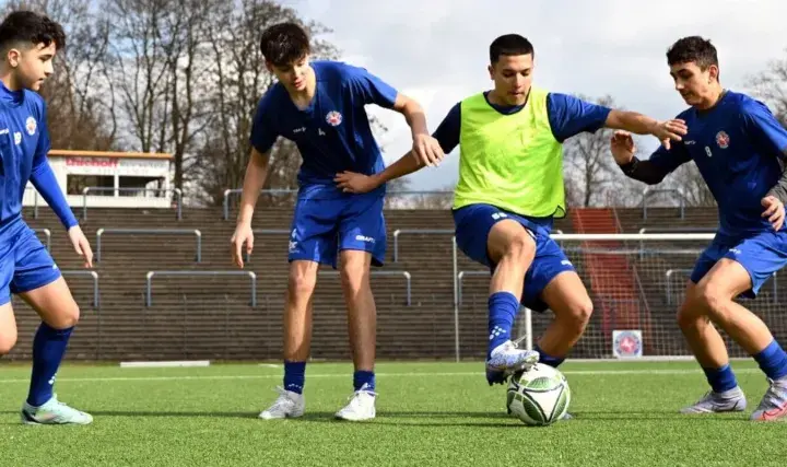 Vier junge Fußballer im C-Jugend-Training üben auf dem Kunstrasen. Einer dribbelt den Ball, die anderen verteidigen.