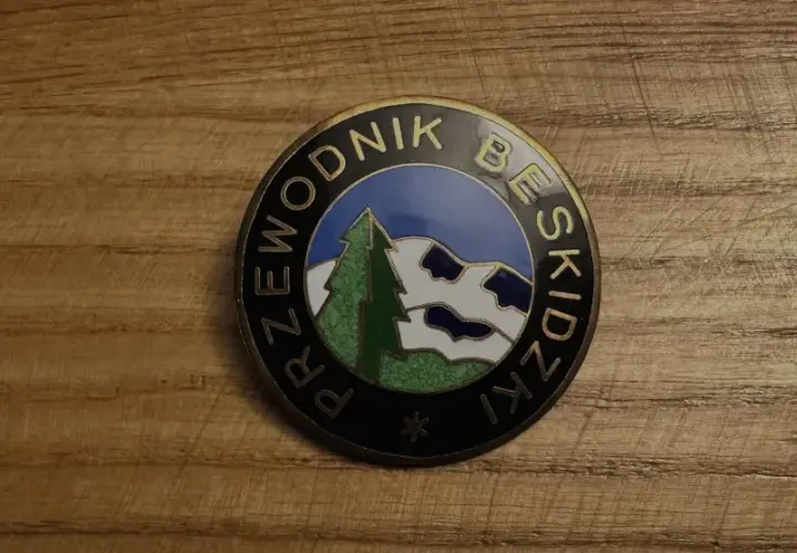 Odznaka z napisem "Przewodnik Beskidzki" i malowniczym krajobrazem górskim.