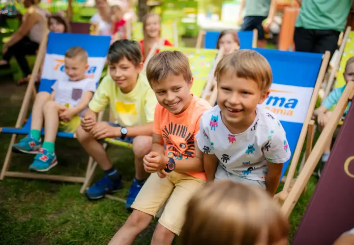 Uśmiechnięte dzieci siedzą na leżakach w parku. To idealne miejsce na letnie zabawy, jak w najlepszych parkach dla dzieci.