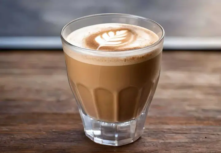 Ein Glas mit cremigem Espresso mit Milch, spanisch. Latte Art Blattmuster auf dem Milchschaum.