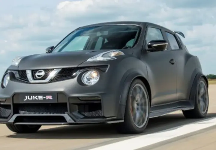 Nissan Juke-R gris oscuro, con alerón trasero y llantas deportivas, circulando por una pista.