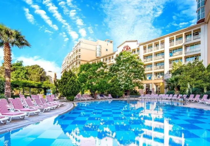 Basen z leżakami i palmą przy hotelu Alba w Bułgarii. Słoneczny dzień, błękitne niebo z chmurami.