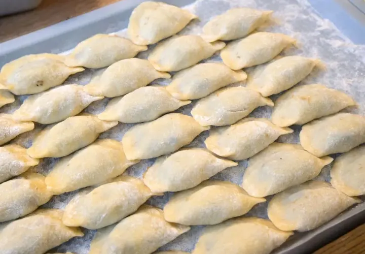 Ułóż surowe pierogi na tacy, posypane mąką, aby wiedzieć, jak przechowywać pierogi.