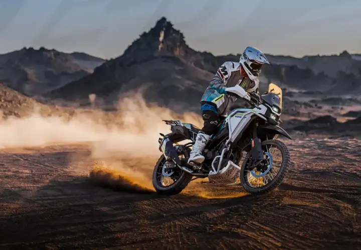 Motociclista en una CF Moto 450 MT, levantando polvo en un paisaje desértico. Conoce la cf moto 450 mt ficha técnica.