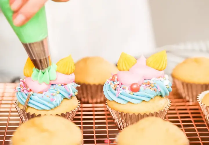 Decorazione di cupcake con crema al burro colorata, zuccherini e perline.
