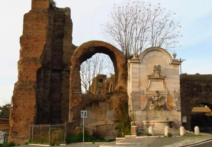 Antica porta furba metro, con fontana e rovine romane.