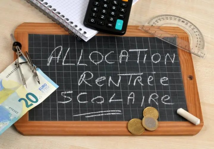 Tableau noir avec "Allocation Rentrée Scolaire" écrit à la craie. Un billet de 20 euros, des pièces, une calculatrice et un compas suggèrent un dépassement de plafond budgétaire.