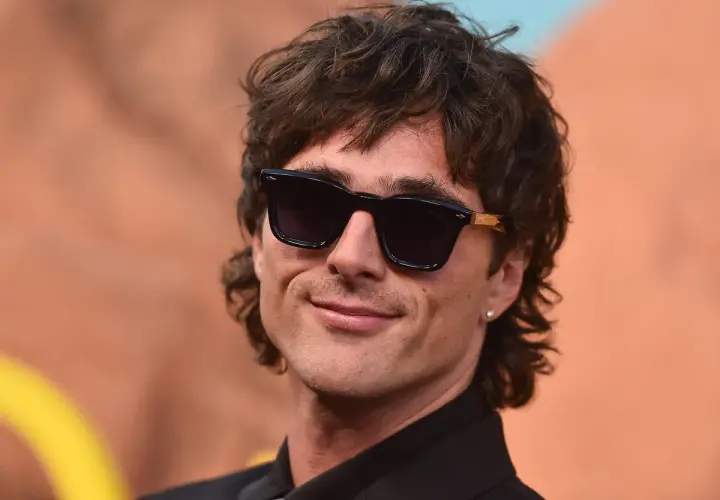 Hombre con corte de pelo moderno, gafas de sol oscuras y sonrisa. Un estilo que anticipa el corte de pelo hombre 2026.