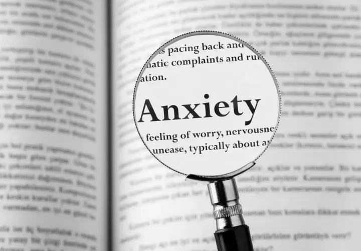 Lupa powiększa hasło "Anxiety" w książce, opisując uczucie niepokoju, które może towarzyszyć fobiom.