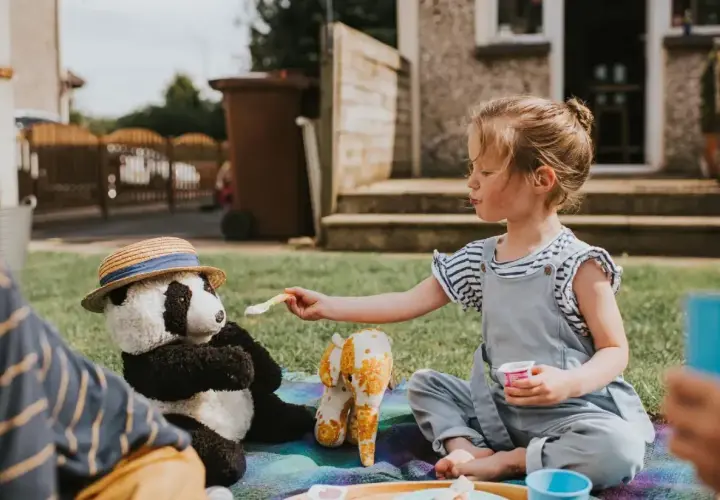 Dziewczynka karmi pluszową pandę na pikniku. Wspaniałe zabawy dla 5-6 latków w domu i ogrodzie.