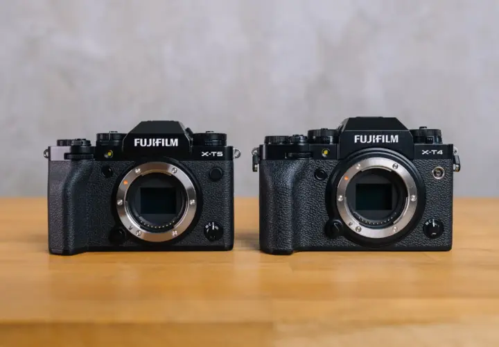 Dwa aparaty Fujifilm: X-T5 i X-T4, stojące obok siebie na drewnianym stole.