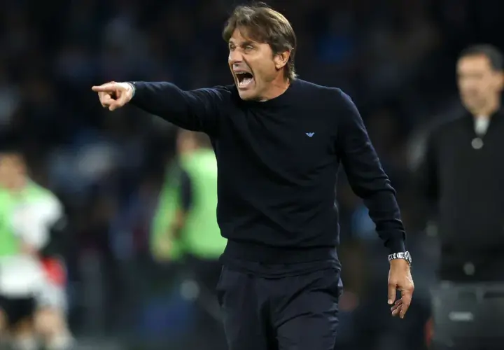 Antonio Conte, znany z taktyki catenaccio, krzyczy i wskazuje palcem, instruując zawodników na boisku.