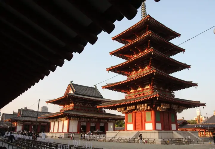 Pięciopiętrowa pagoda i inne budynki świątyni buddyjskiej w Japonii, z tradycyjnymi dachami i czerwonymi detalami.