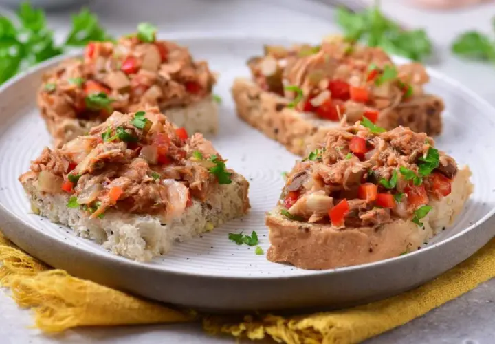 Chrupiące grzanki z makrelą w pomidorach, posypane natką pietruszki. Idealna przekąska na szybki lunch.