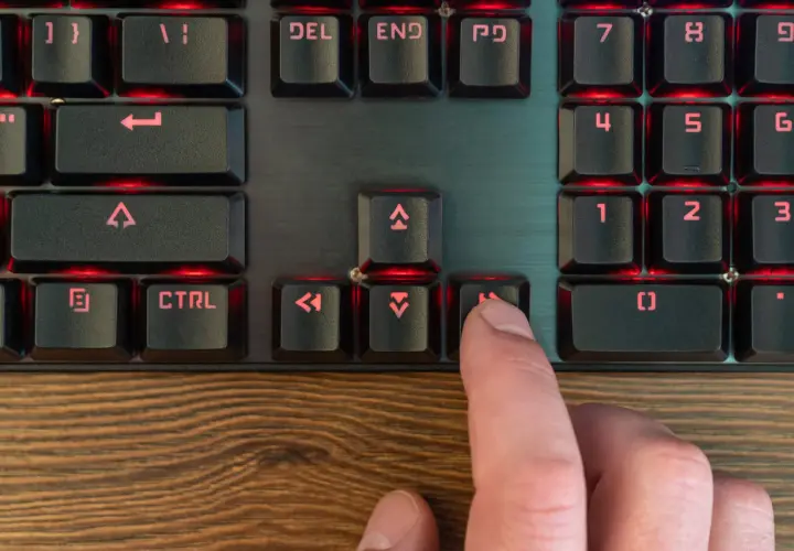 Palec naciska klawisz "Home" na podświetlanej klawiaturze programisty, co może być częścią skrótu klawiszowego.