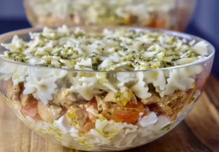 Pyszna, warstwowa sałatka z kurczakiem i makaronem farfalle, polana sosem pesto. Idealna na najlepsza sałatka z kurczakiem na imprezę!