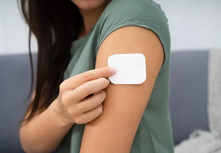 Kobieta przykleja plaster antykoncepcyjny. Przed użyciem warto zapoznać się z przeciwwskazaniami.