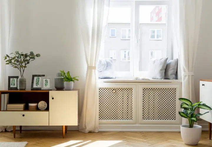 Elegancka osłona kaloryfera pod oknem, z ażurowym wzorem, stanowi stylowe rozwiązanie, jak zasłonić kaloryfer pod oknem, dodając wnętrzu uroku.