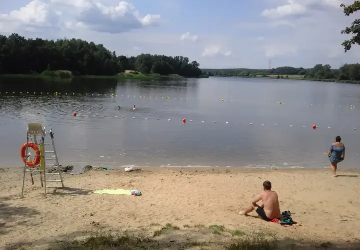 Słoneczny dzień nad zalewem Rybnik. Kąpielisko z ratownikiem, piaszczysta plaża i ludzie kąpiący się w wodzie.