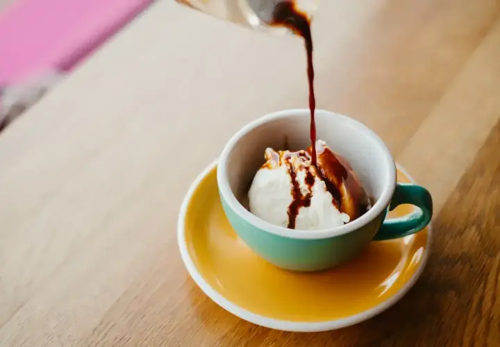 Gorące espresso zalewa kulkę lodów waniliowych w filiżance. Klasyczne lody po włosku, idealne na deser.