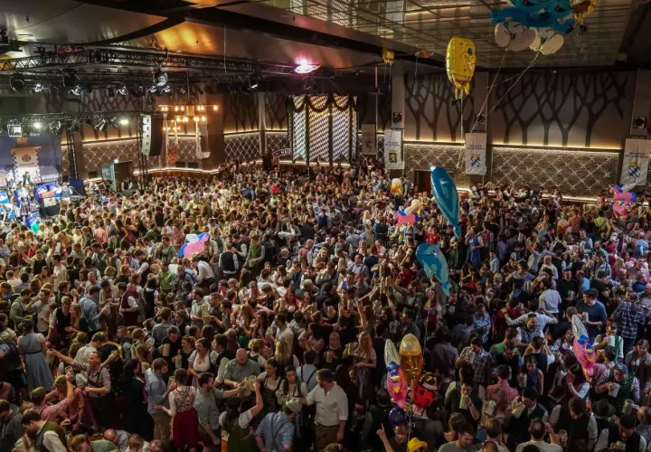 Volles Festzelt am Nockherberg 2026 mit vielen Menschen in Tracht, die Bierkrüge schwenken. Luftballons steigen auf.