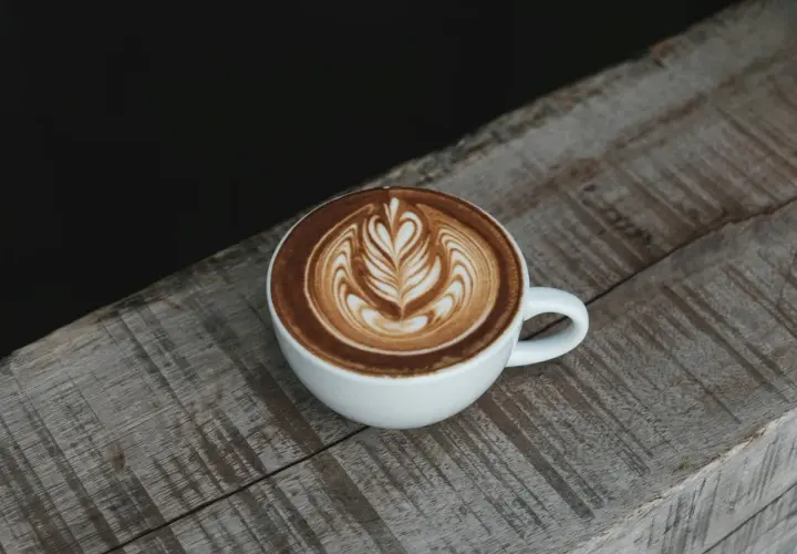 Eine Tasse Cappuccino mit Latte Art auf einem Holztisch. Die Menge des Kaffees ist perfekt für einen Genussmoment.