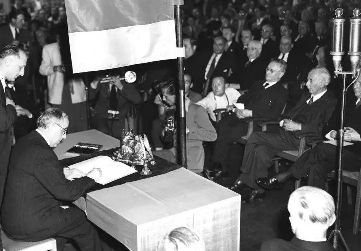 Männer in Anzügen versammeln sich, um die Unterzeichnung des Grundgesetzes zu beobachten. Wann wurde das Grundgesetz geschrieben? Am 23. Mai 1949.