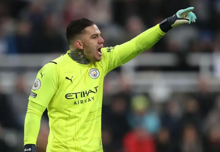 Bramkarz Manchester City w żółtej koszulce, z podniesioną ręką, gotowy do akcji. Skład Manchester City.