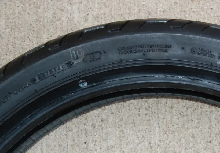 Detalle de la nomenclatura de llantas de motocicleta, mostrando información de carga, presión y composición.