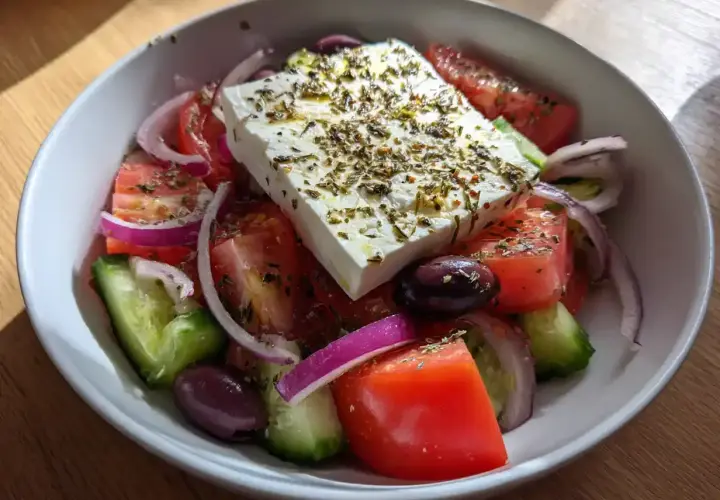 En fräsch grekisk sallad med fetaost, tomater, gurka, rödlök och oliver, toppad med örter.