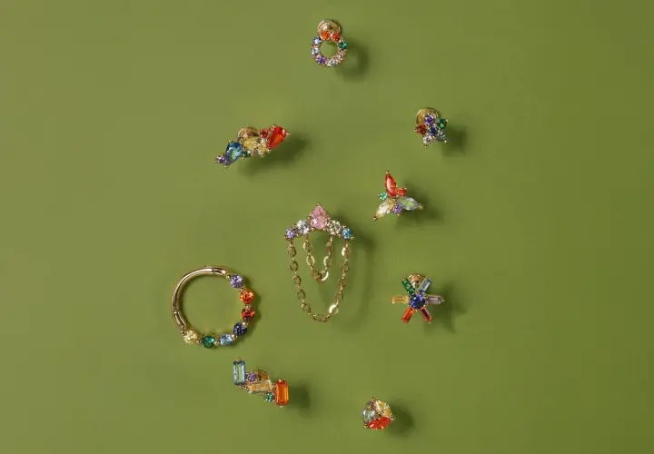 Kolorowe, błyszczące ozdoby do uszu, w tym kolczyki i kółko, prezentują różnorodność stylów piercingu.