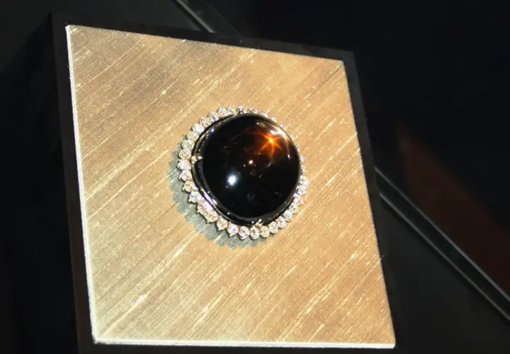 Ein glänzender schwarzer Saphir mit einem Stern-Effekt, umgeben von kleinen Diamanten. Seine geheimnisvolle schwarzer saphir bedeutung fasziniert.