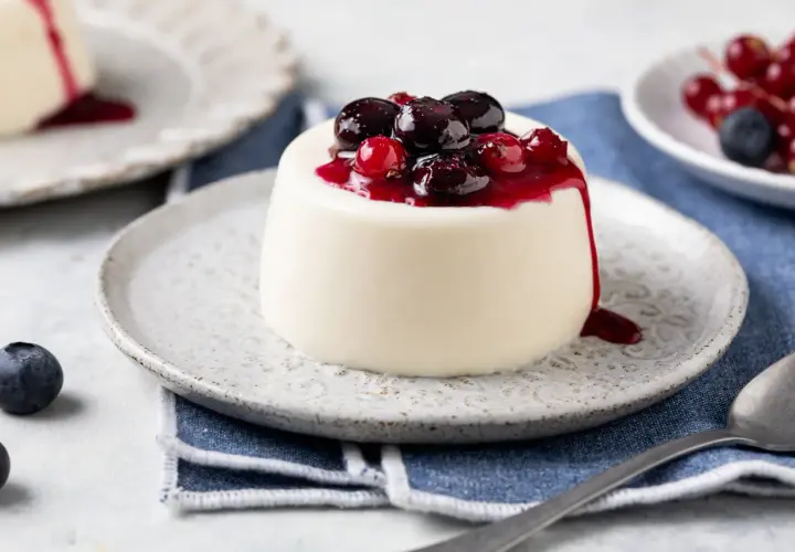 Panna cotta bianca con topping di frutti di bosco e salsa rossa. Ingredienti panna cotta freschi e invitanti.