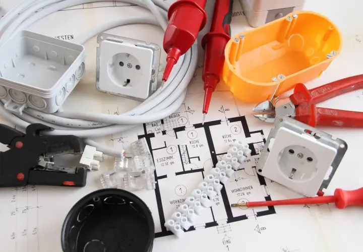 Narzędzia i materiały do wymiany instalacji elektrycznej bez kucia: przewody, puszki, gniazdka, złączki, kombinerki, ściągacz izolacji, śrubokręt i schemat instalacji.