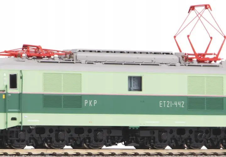 Zielona lokomotywa na prąd PKP ET21-442 z czerwonymi pantografami na dachu, stojąca na torach.