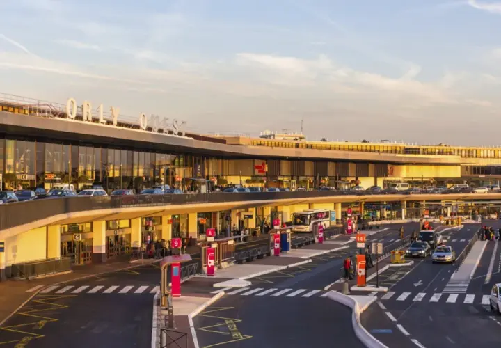 Orly Ouest, jedno z lotnisk w Paryżu, tętni życiem. Samochody, autobusy i pasażerowie tworzą dynamiczny obraz.