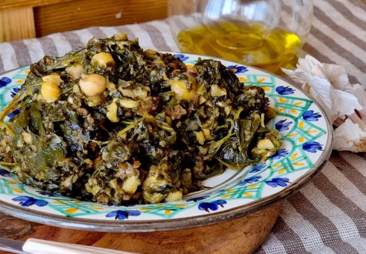 Un plato de garbanzos con espinacas, cocinado con ajo y aceite de oliva.