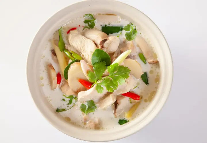 En skål med krämig tom kha gai med kyckling, svamp, chili och koriander.