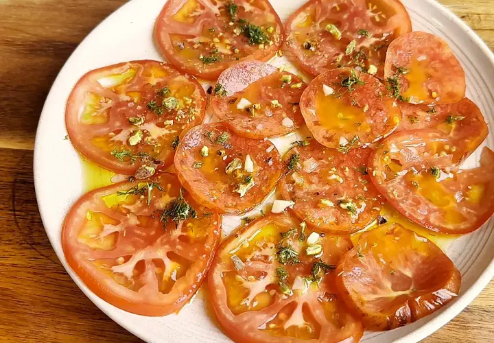 Carpaccio de tomate fresco con aceite de oliva, ajo picado y hierbas aromáticas. Un plato ligero y lleno de sabor.