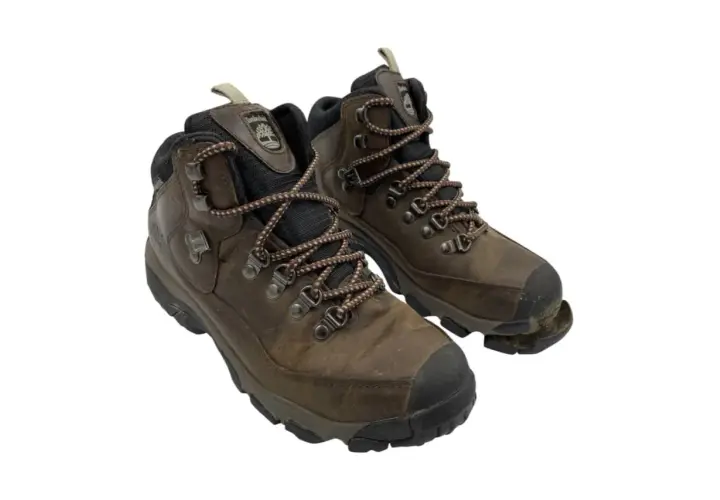 Well-worn brown hiking boots, one with the sole coming off, showing signs of many adventures.