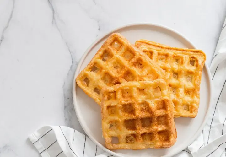 Trois gaufres au sarrasin dorées et croustillantes sur une assiette blanche, prêtes à être dégustées.