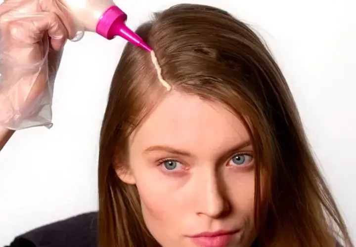 Mujer se aplica tinte en el cabello. Considera los tintes con amoniaco: ventajas y desventajas antes de usarlos.