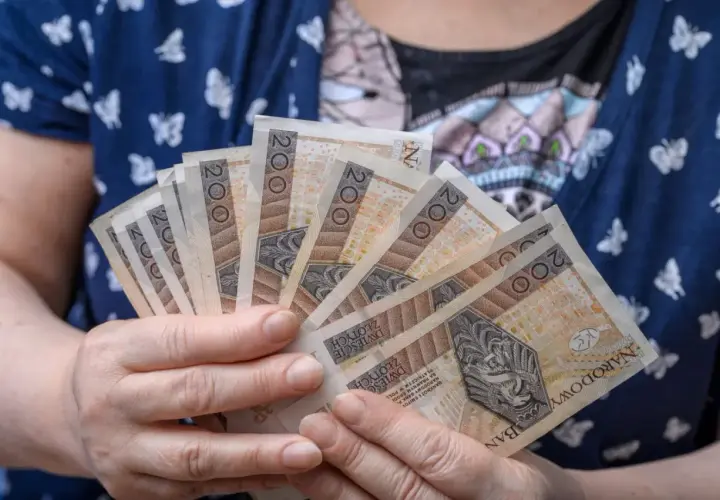 Dłonie trzymające kilka banknotów po 200 zł. Czy to przyszłość renty wdowiej? Zmiany w przepisach mogą wpłynąć na finanse.