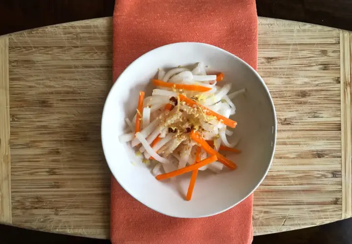A refreshing namasu recipe with julienned daikon radish and carrots, seasoned with sesame seeds and a hint of citrus zest.