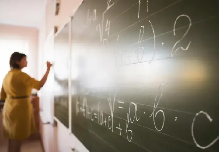 Nauczycielka pisze wzory matematyczne na tablicy. To jak art 20 kn, gdzie każdy symbol ma swoje znaczenie.