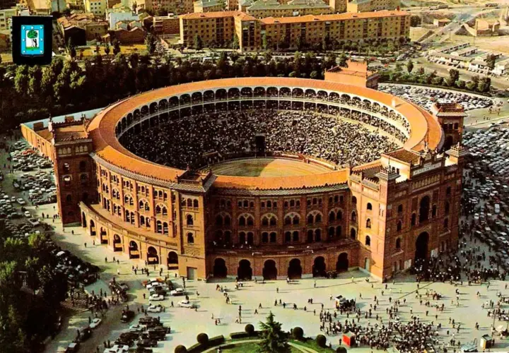 Vista aérea de la plaza de toros Las Ventas, llena de espectadores, con coches aparcados alrededor y gente paseando.